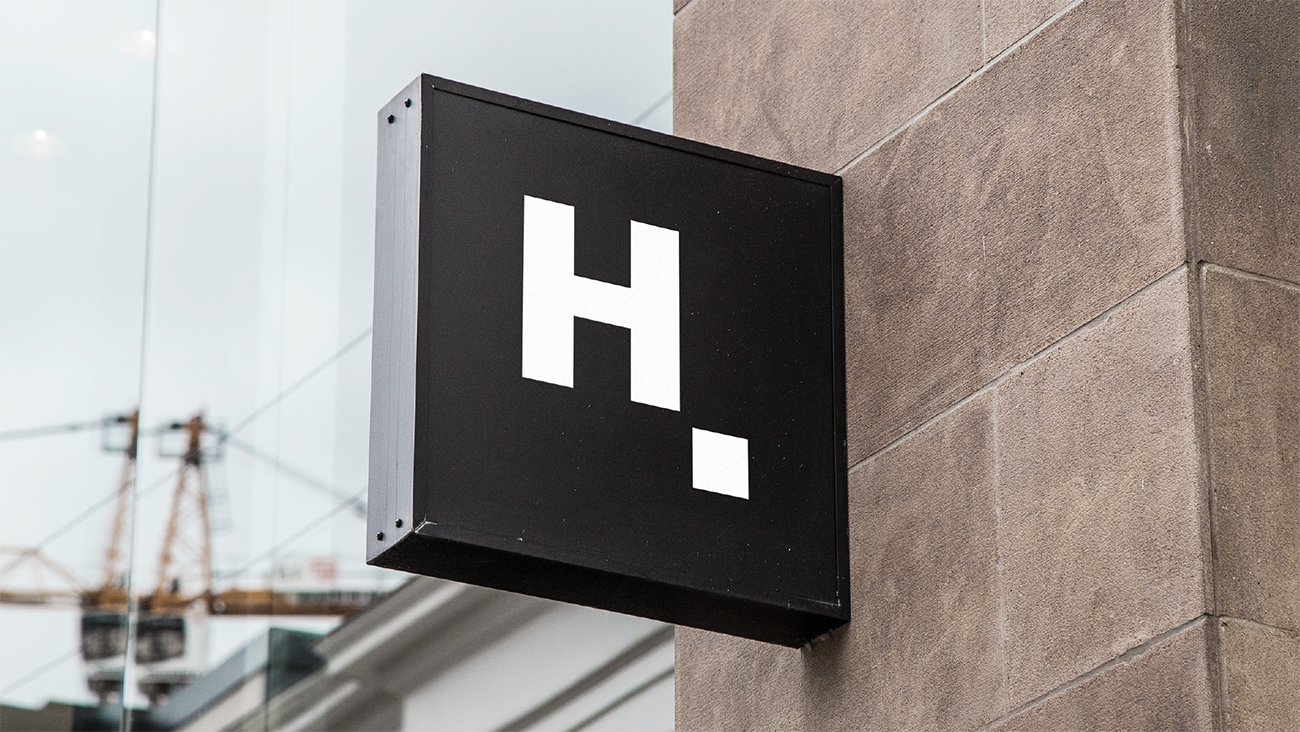 Square Handsontable “H.” logo sign mounted on a stone building